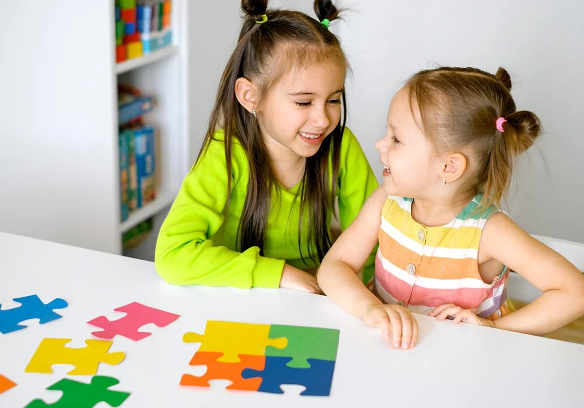 two children smiling together over a colorful puzzle