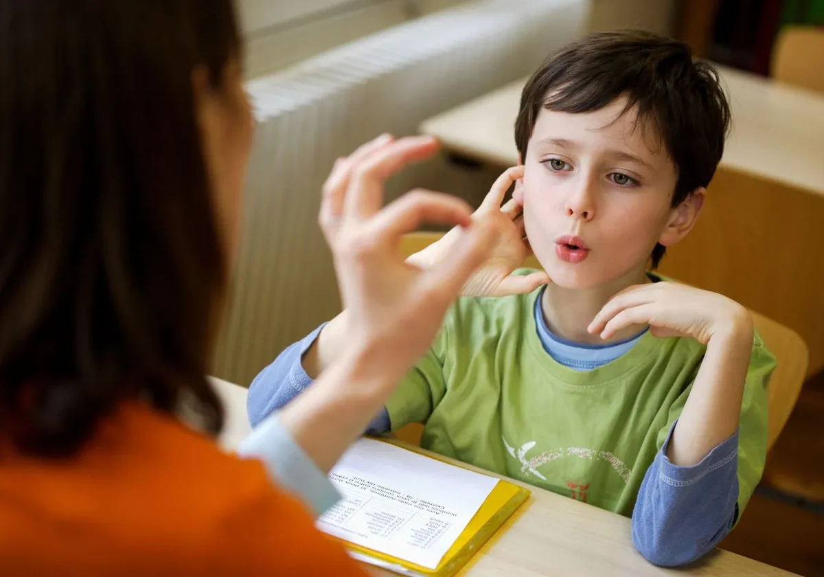 speech-language pathologist working one-on-one with a child at a table